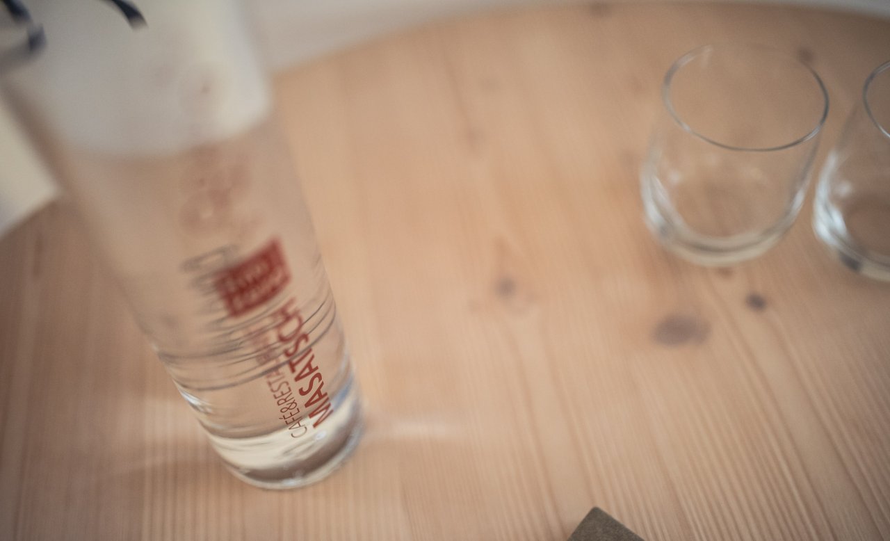 Wasserflasche mit Masatsch-Logo und zwei Gläsern auf Holztisch im Meetingraum