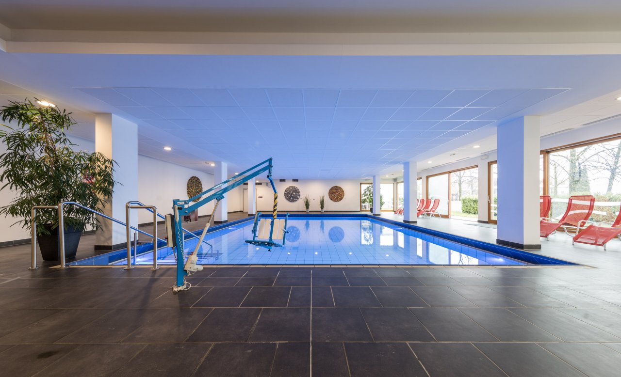 Barrierefreier Indoor-Pool im Hotel Masatsch mit Hebelift und roten Liegestühlen