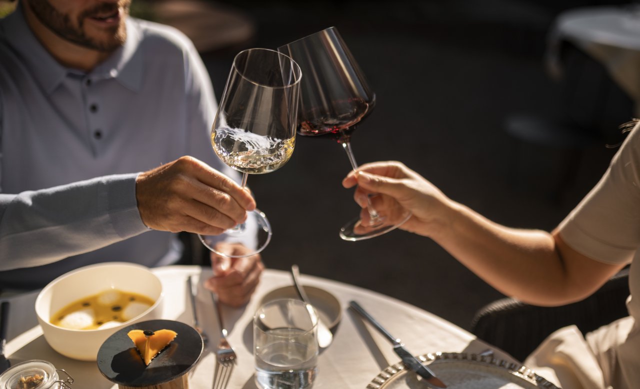 Two hands clinking wine glasses at Masatsch restaurant