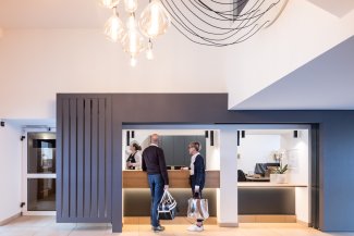 Moderne Rezeption im Hotel Masatsch mit zwei Gästen davor