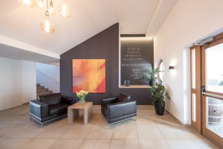 Gemütliche Sitzecke im Hotel Masatsch mit schwarzen Ledersesseln, frischen Blumen und moderner Kunst