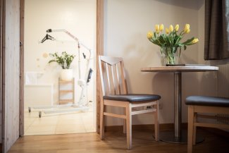 Nahaufnahme eines Zimmers im Hotel Masatsch mit Tisch, Stuhl und frischen Blume