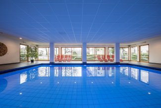 Indoor-Pool im Hotel Masatsch mit roten Liegen im Hintergrund