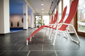 Rote Liegen auf dunklem Plattenboden am Indoor-Pool im Hotel Masatsch