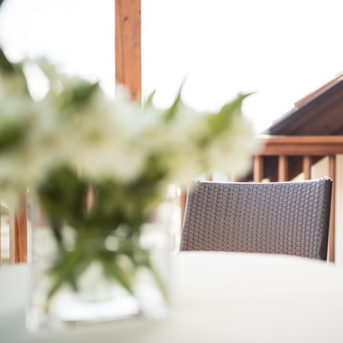 Tisch im Hotel Masatsch mit Glasvase und weißen Blumen