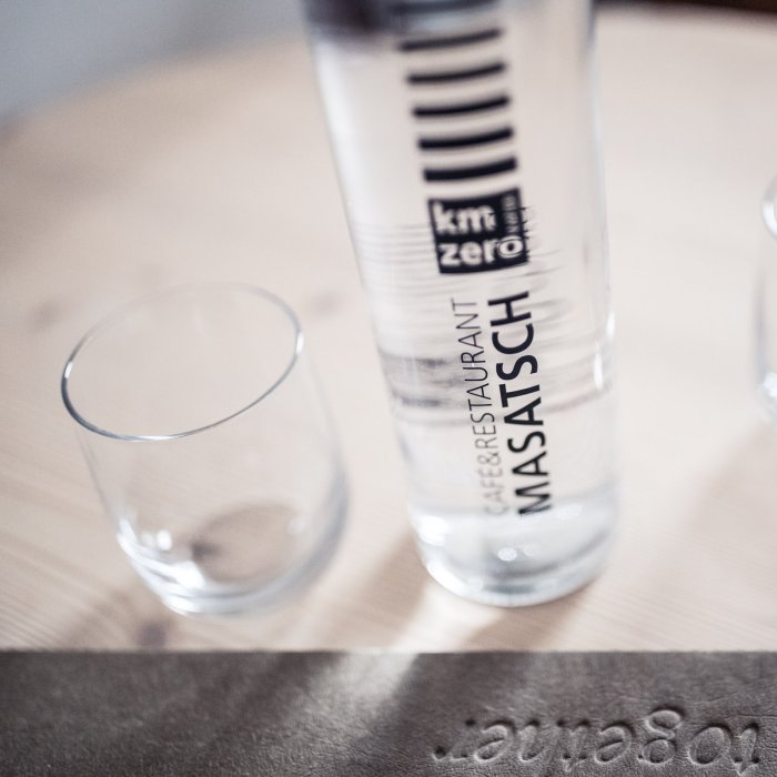Wasserflasche und Glas mit Aufschrift km ZERO im Hotel Masatsch