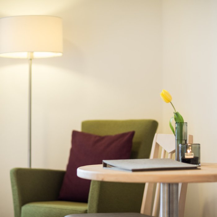 Moderner grüner Stuhl mit gelber Tulpe im Vordergrund im Hotel Masatsch